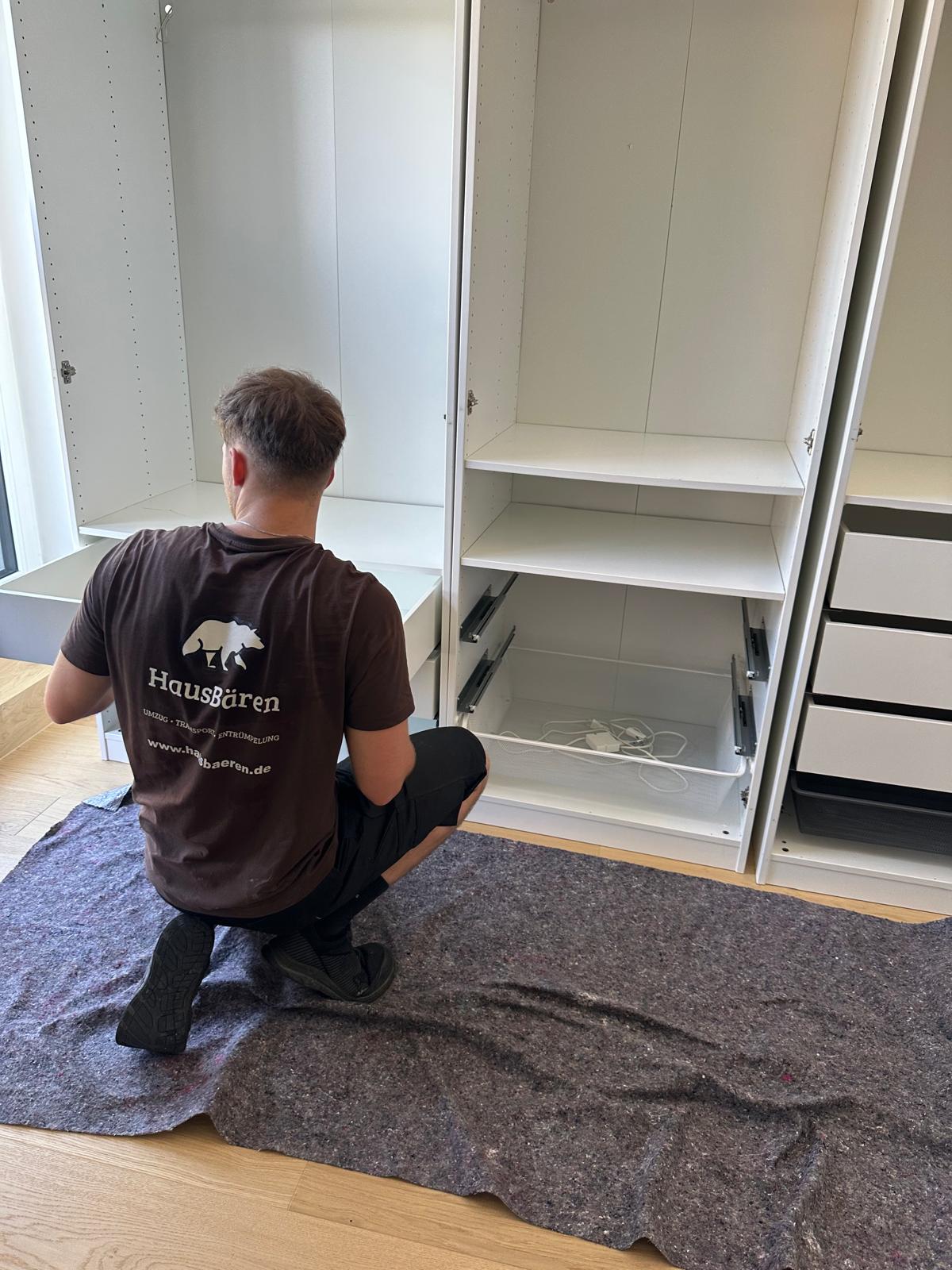 HausBären-Mitarbeiter montiert einen großen weißen Kleiderschrank