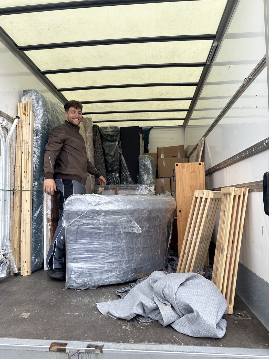 Freundlicher HausBären-Mitarbeiter im sorgfältig beladenen Umzugsfahrzeug
